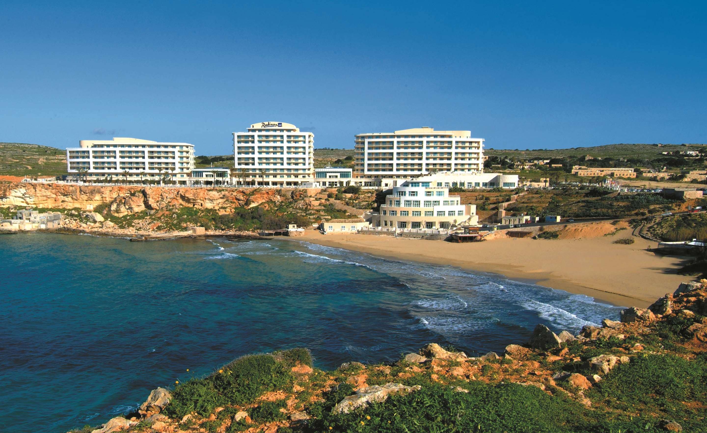 Aerial view of luxury Malta hotel overlooking the Mediterranean sea at sunset — search: luxury hotel Malta Mediterranean aerial view